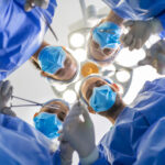 Surgeons standing above of the patient before surgery. Multi-ethnic healthcare workers performing surgery on patient at operation theater.